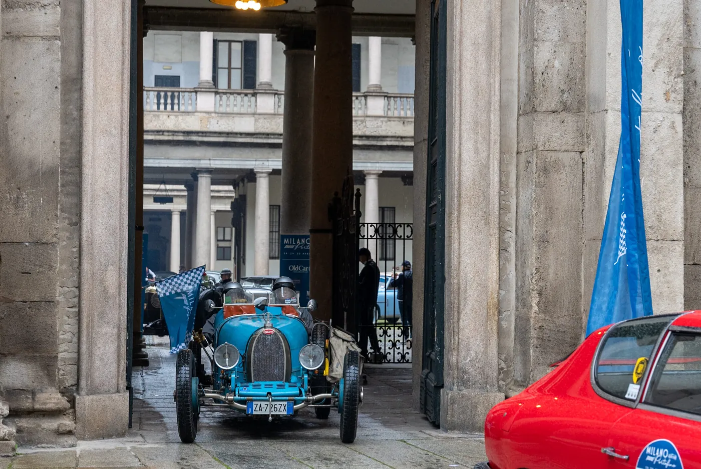Auto storica azzurra attraversa un portone milanese